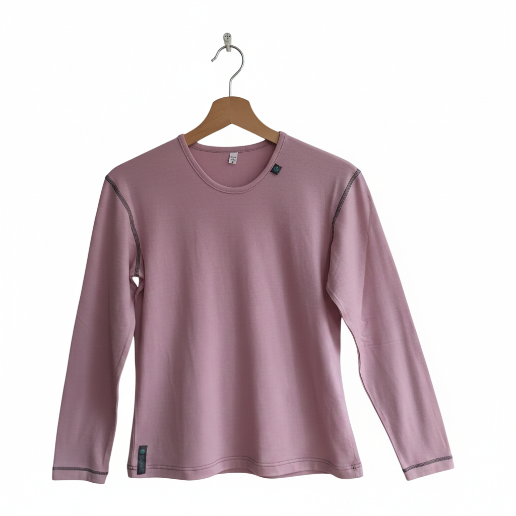 A dusty pink long-sleeve merino wool crewneck top hanging on a wooden hanger against a plain light gray wall.