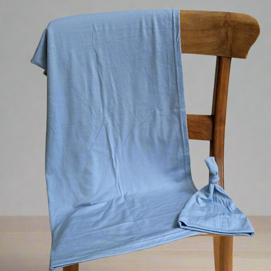 Light blue blanket draped over a wooden chair against a neutral background