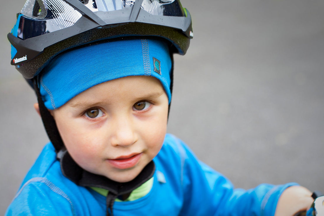 Child wearing blue merino beanie under cycling helmet