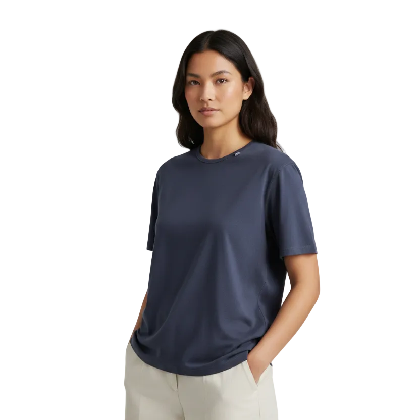 A woman modeling a short-sleeve crewneck merino wool t-shirt in navy blue, paired with light beige trousers, against a plain light gray studio background.